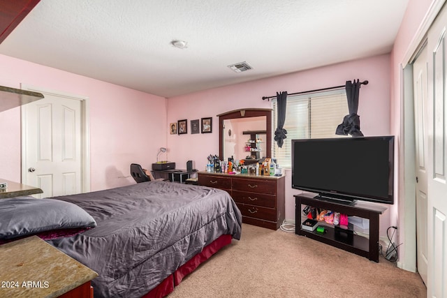 carpeted bedroom with multiple windows, a textured ceiling, and a closet