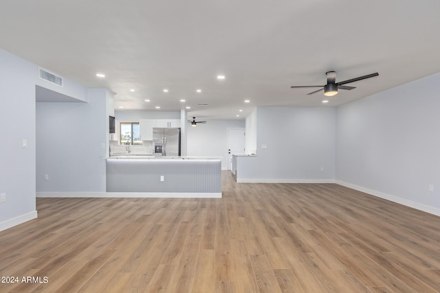 unfurnished living room with ceiling fan and light hardwood / wood-style flooring