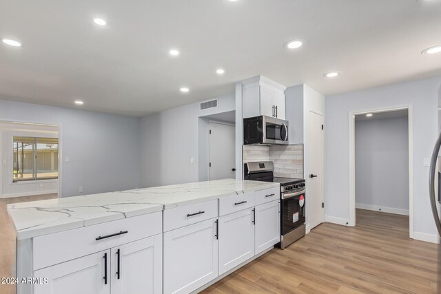 kitchen featuring appliances with stainless steel finishes, tasteful backsplash, light stone counters, light hardwood / wood-style floors, and white cabinetry