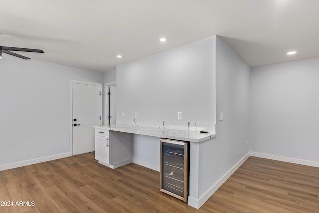 interior space with bar area, wood-type flooring, ceiling fan, and beverage cooler