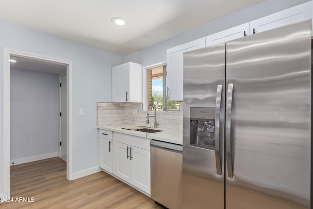 kitchen with sink, white cabinets, light hardwood / wood-style flooring, stainless steel appliances, and tasteful backsplash