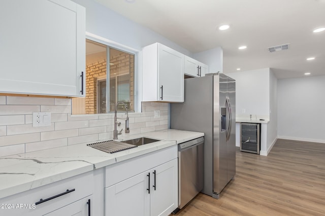 kitchen with white cabinets, light hardwood / wood-style floors, backsplash, and dishwasher