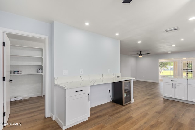 kitchen with ceiling fan, built in features, light stone countertops, white cabinetry, and hardwood / wood-style flooring