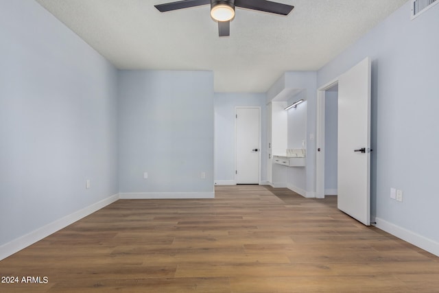 unfurnished bedroom featuring ensuite bath, a textured ceiling, ceiling fan, and light hardwood / wood-style flooring