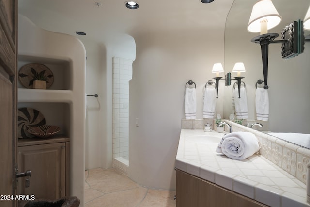 bathroom featuring vanity, tiled shower, and tile patterned flooring