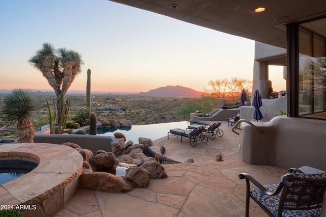 patio terrace at dusk featuring a mountain view