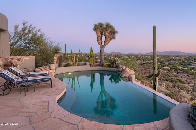 pool at dusk featuring a patio area and a mountain view