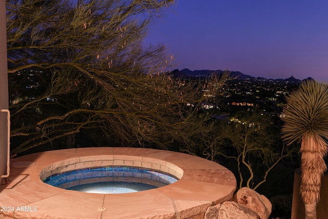 pool at dusk featuring an in ground hot tub