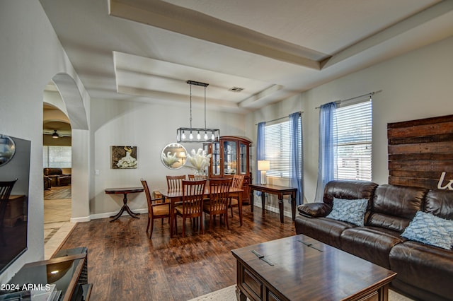 living room with dark wood-type flooring and a tray ceiling