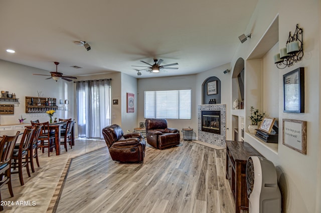 living room featuring ceiling fan, wood-type flooring, and a fireplace