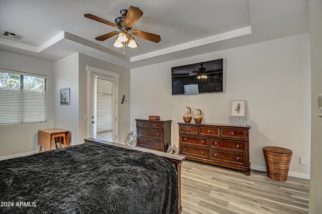 bedroom featuring a tray ceiling, light hardwood / wood-style floors, and ceiling fan