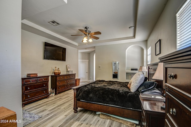 bedroom with a tray ceiling, ceiling fan, and light wood-type flooring