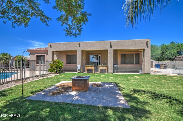 rear view of house with a fenced in pool, a fire pit, a yard, and a patio area