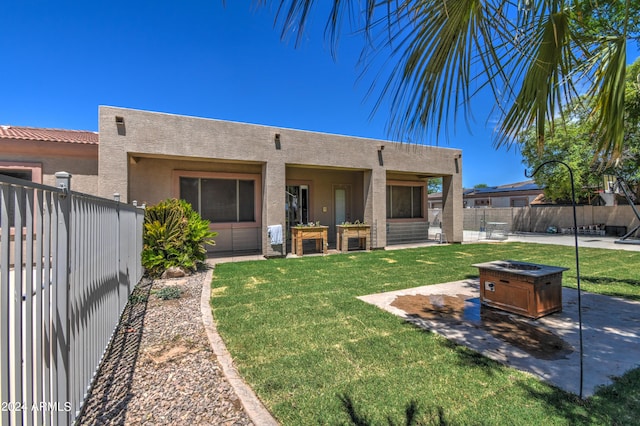 rear view of property featuring a fire pit and a lawn