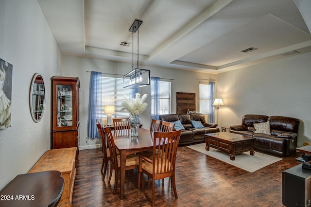 dining area with a tray ceiling and dark hardwood / wood-style flooring