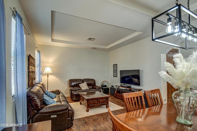 living room with a chandelier, wood-type flooring, and a raised ceiling