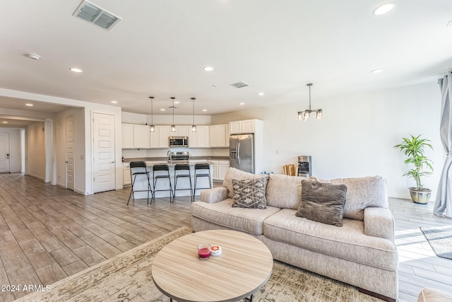 living room featuring sink, light wood-type flooring, and a notable chandelier