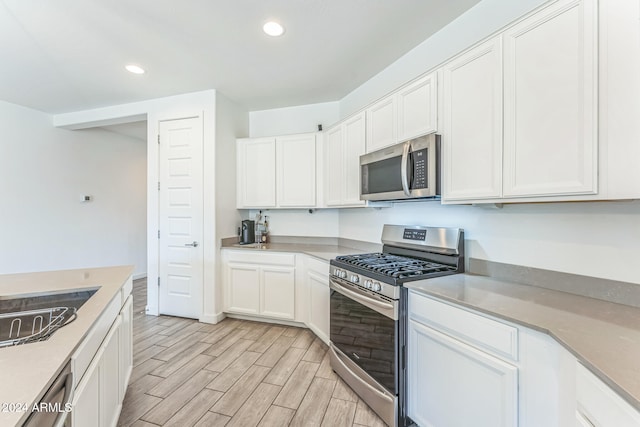 kitchen featuring white cabinetry, sink, light hardwood / wood-style flooring, and appliances with stainless steel finishes