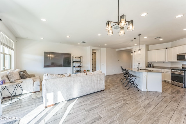 living room with light hardwood / wood-style floors, sink, and a notable chandelier