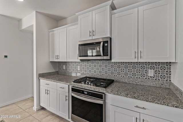 kitchen with light tile patterned flooring, white cabinetry, appliances with stainless steel finishes, decorative backsplash, and light stone countertops