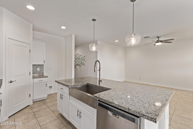 kitchen featuring pendant lighting, a center island with sink, stainless steel dishwasher, light tile patterned flooring, and a sink