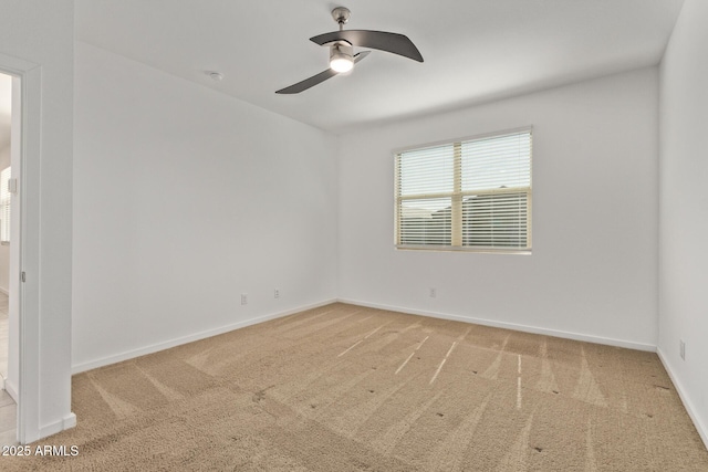 spare room with carpet, baseboards, and a ceiling fan