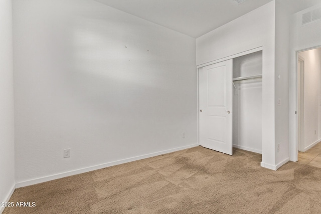 unfurnished bedroom with carpet floors, visible vents, baseboards, and a closet