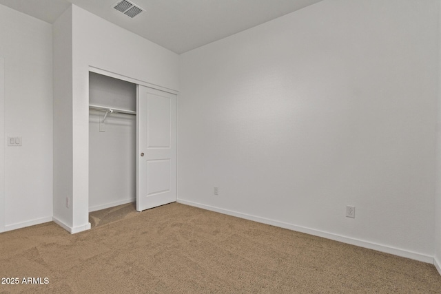 unfurnished bedroom with baseboards, a closet, visible vents, and carpet flooring