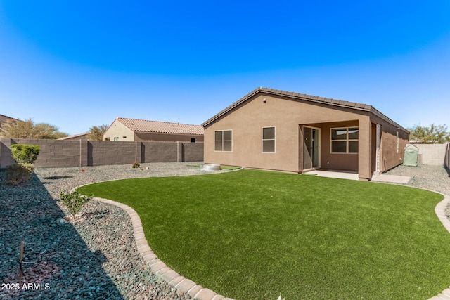 rear view of house featuring a patio, stucco siding, a lawn, a fenced backyard, and a tiled roof