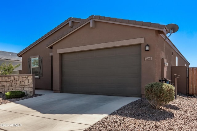 view of front of house featuring a garage, driveway, fence, and stucco siding