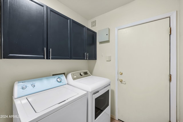 laundry room with washing machine and dryer and cabinets