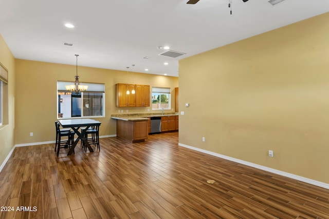 kitchen featuring stainless steel dishwasher, hanging light fixtures, ceiling fan with notable chandelier, and dark hardwood / wood-style flooring