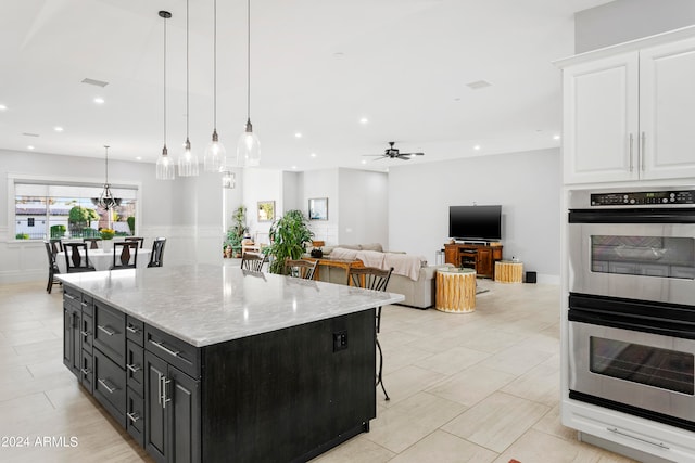 kitchen featuring white cabinetry, a kitchen bar, pendant lighting, a center island, and stainless steel double oven