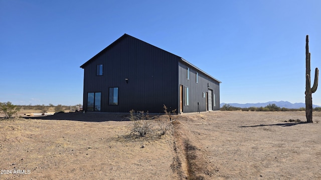 rear view of property with a mountain view and an outdoor structure