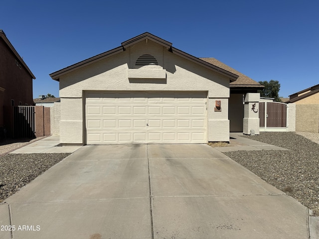 ranch-style home with stucco siding, an attached garage, concrete driveway, and a gate