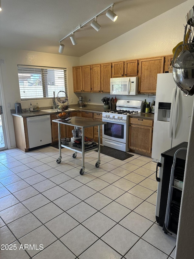 kitchen with light tile patterned floors, white appliances, brown cabinetry, and vaulted ceiling