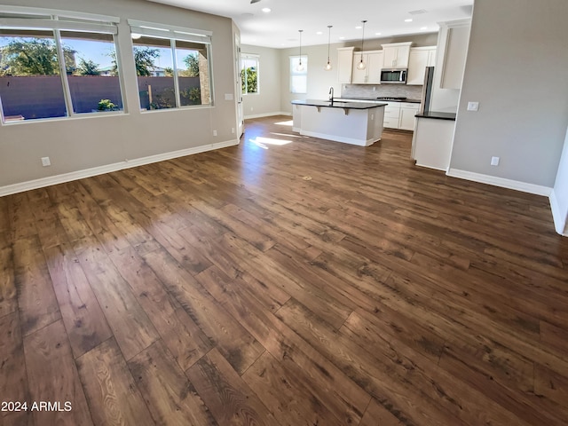 unfurnished living room with sink and dark wood-type flooring