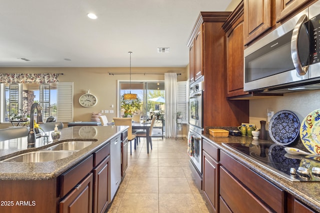 kitchen with light tile patterned floors, stainless steel appliances, visible vents, a sink, and dark stone countertops