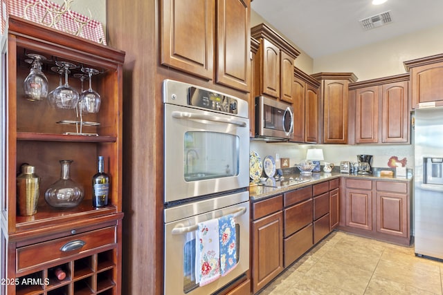 kitchen featuring stainless steel appliances, dark stone counters, visible vents, and light tile patterned floors