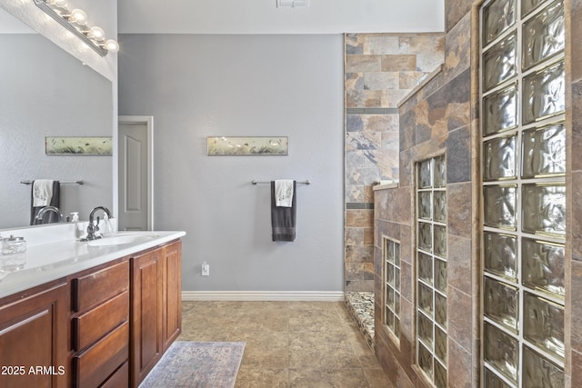 full bathroom featuring baseboards, a walk in shower, and vanity