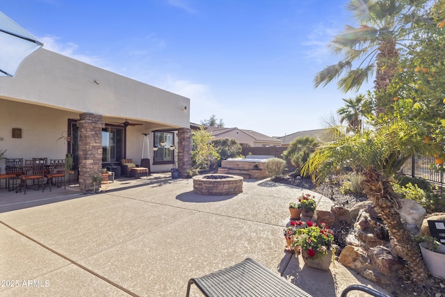 view of patio with a fire pit, fence, and a ceiling fan