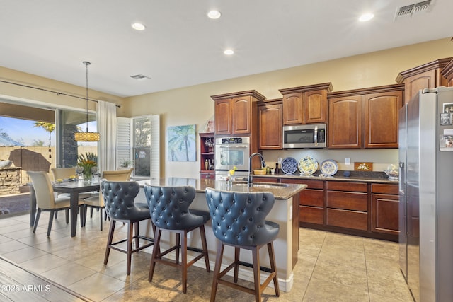 kitchen featuring stainless steel appliances, a center island with sink, a sink, and visible vents