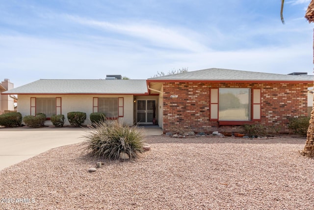 view of front of property with concrete driveway, brick siding, and roof with shingles