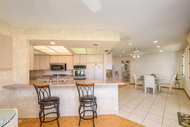 kitchen featuring a kitchen breakfast bar, kitchen peninsula, ceiling fan, and stainless steel appliances