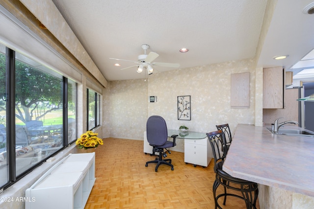 office area with a textured ceiling, light parquet flooring, ceiling fan, and sink