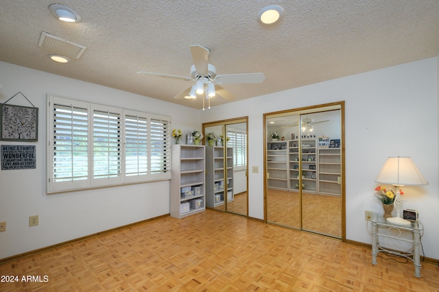 unfurnished room with ceiling fan, a textured ceiling, and light parquet flooring