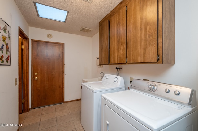 clothes washing area featuring cabinets, a textured ceiling, sink, light tile patterned floors, and washing machine and dryer