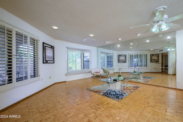 workout room with a textured ceiling, ceiling fan, and light parquet flooring