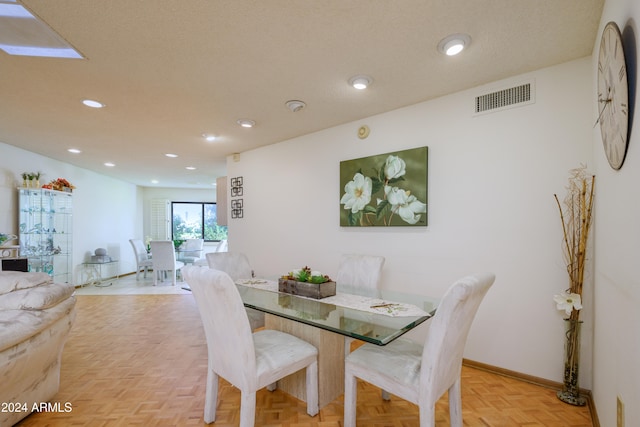 dining space featuring light parquet flooring and a textured ceiling