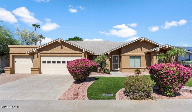 ranch-style home featuring a garage and a front lawn